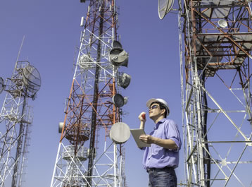 Man in hard hat standing by 3 radio towers
